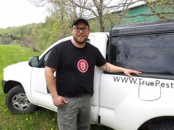 Casey Johnson, Owner and CEO of True Pest and Rodent Solutions LLC, standing next to his service truck in Vermont